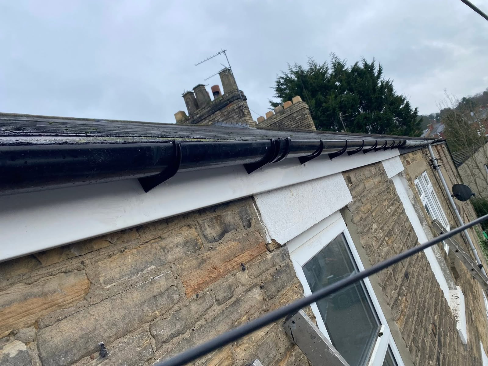 Gutter repairs in Glasgow: black uPVC gutter run fitted along a stone property